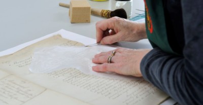 Closeup of hands working on preservation of a manuscript